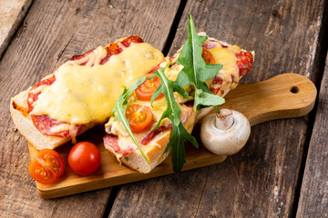 Homemade pizza on a baguette with cheese and arugula, pizza on bread. Italian sandwich. Wooden...