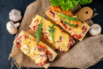 Homemade pizza on a baguette with raw and sausages and herbs, sandwich pizza top view.
