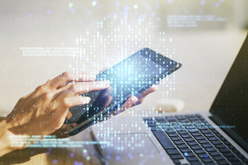 Creative code skull hologram and finger presses on a digital tablet on background, cybercrime and hacking concept. Multiexposure