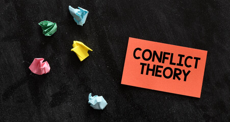CONFLICT THEORY words on a small red piece of paper and black background.
