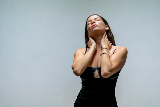 Beautiful woman with eyes closed touching her neck