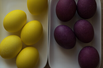 Bright and beautiful Easter eggs, purple and yellow, on a white plate. Christ is risen. Happy...