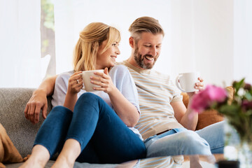 Happy couple relaxing on the sofa at home - 500863825