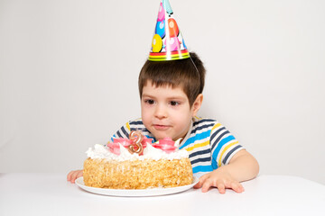 A child in a festive cap blows out the candles on the cake on his birthday