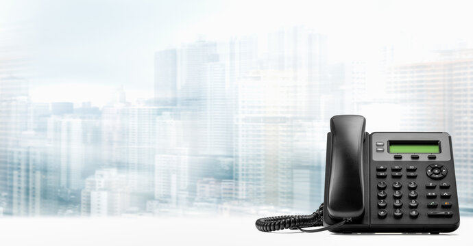landline telephone with VOIP on white table on blurred city background. customer service support, call center concept. Modern VoIP or IP phone. copy space