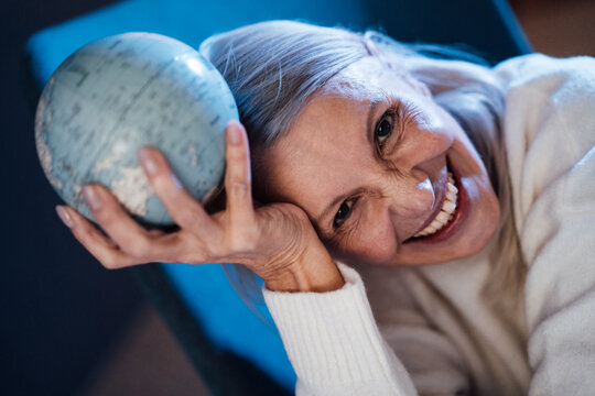 Happy senior woman holding globe in hand