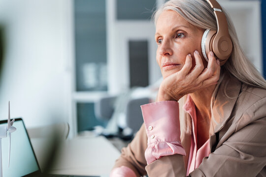 Businesswoman listening music through headphones at office