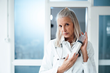 Senior female doctor holding syringe at hospital