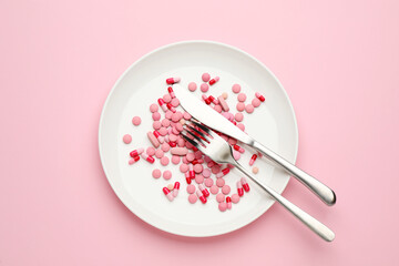Plate with weight loss pills and cutlery on pink background, top view