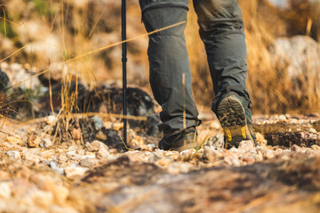 Close up mountaineering boots walking on rocky mountains at  outdoor. Tourist walks on adventure trip in natural at holidays. Travel lifestyle concept