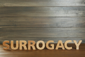 Word Surrogacy made of wooden letters on table, space for text