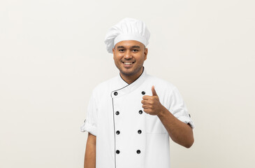 Smiling Young handsome asian man chef in uniform with hat standing posting looking at camera showing thumbs up on isolated. Cooking man Occupation chef or baker in kitchen restaurant and hotel.
