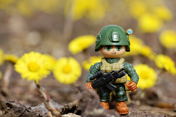 Toy soldier on background of spring flowers of coltsfoot. Concept of military forces, modern war