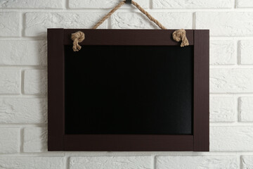 Clean small black chalkboard hanging on white brick wall