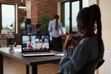 Businesswoman discussing through videocall with coworkers about marketing strategy of startup project. African american company team leader in video call digital conference with executive board.