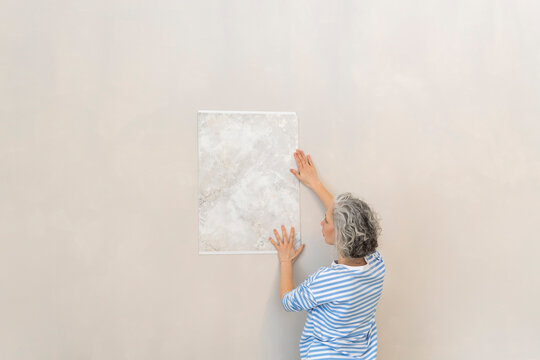 Woman analyzing wallpaper sample on wall