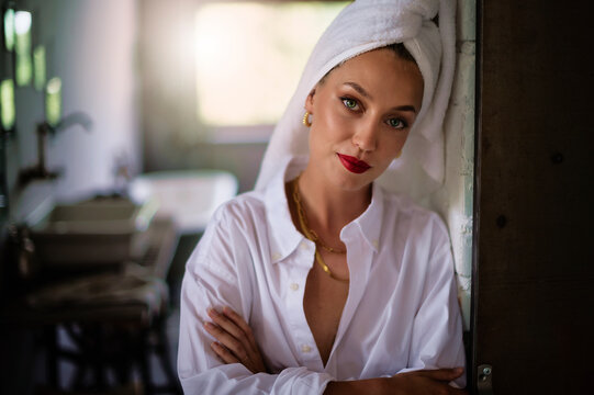 Portrait of beautiful woman wearing white shirt and turban towel on head while daydreaming at home