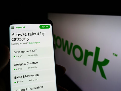 Stuttgart, Germany - 03-28-2022: Person holding smartphone with website of American freelancing platform Upwork Global Inc. on screen with logo. Focus on center of phone display.