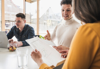 Young business people discussing a document during a meeting in office