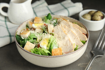Delicious Caesar salad in bowl on grey table, closeup