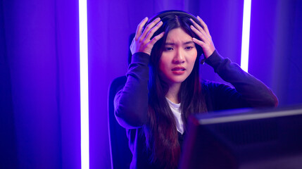 Stressed Boring and loses. Young pretty asian woman playing game computer pc. Female Gamer on headphone playing video game  feeling sadness. Loss and Missed the chance to become a champion