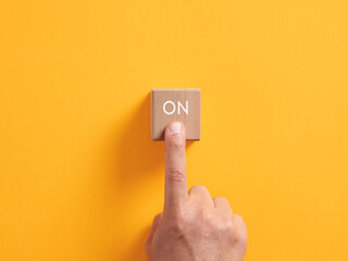Male hand presses on a wooden cube with the word on. Power on push button business startup...