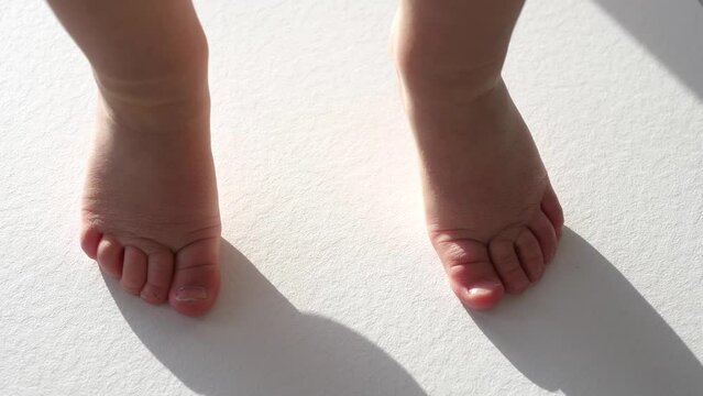 View of bare baby feet dancing on white floor