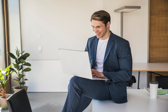 Smiling businessman using laptop in office