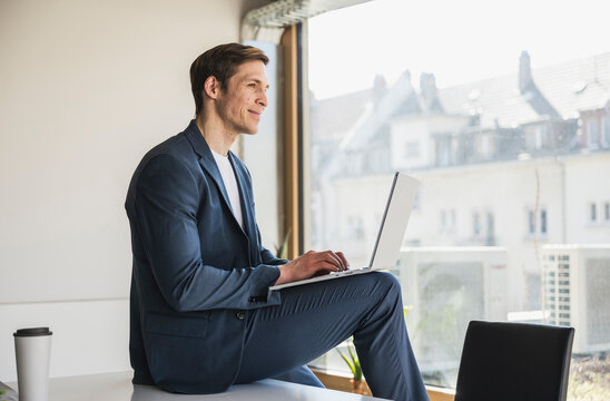 Businessman using laptop at the window in office