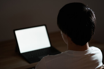 夜中にノートパソコンに向かうアジア人男性