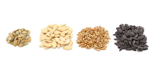 Four piles of pumpkin and sunflower seeds.
