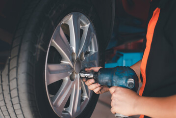 Professional car mechanic changing car wheel in auto repair service., Close up image of expert...