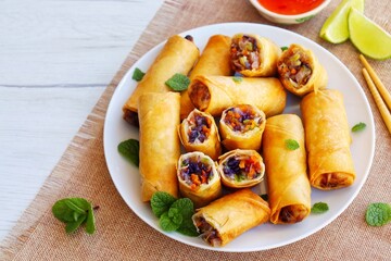 Selective focus on crispy vegetarian spring rolls on plate with white wood table background.Top view.Copy space