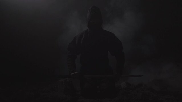 Medieval warrior assassin ninja with sword in aggressive pose in smoke