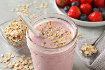 Jar of tasty berry oatmeal smoothie on grey table, closeup