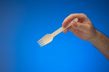 Single use disposable and biodegradable wooden spoon held in hand by Caucasian male. Close up...