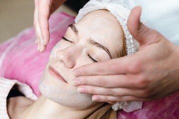 A cosmetologist does a peeling of a young woman's face