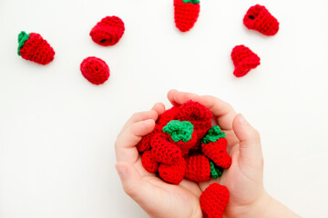 Early harvest. Handmade berries for toy kitchen. Strawberries in a kid hands. Educational, creative games. The child is playing cooking.