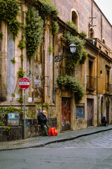 Obraz premium Elderly man sitting watching his phone in the historical center of Catania