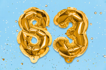 The number of the balloon made of golden foil, the number eighty-three on a blue background with sequins. Birthday greeting card with inscription 83. Numerical digit. Celebration event, template