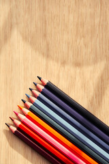 Bright dark colored pencils on the wooden table. Arts and leisure activity and hobby vertical background with copy space