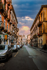 Obraz premium Main street of Catania with the facade of its Cathedral in the background at sunset