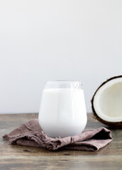Coconut milk in a glass and coconut on a wooden table, side view. Healthy food concept, gluten free diet. lactose free milk.