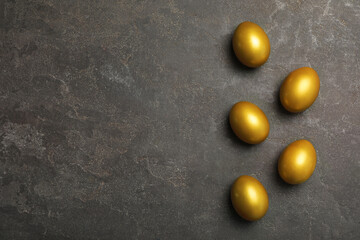 Fototapeta na wymiar Golden eggs on black table, flat lay. Space for text