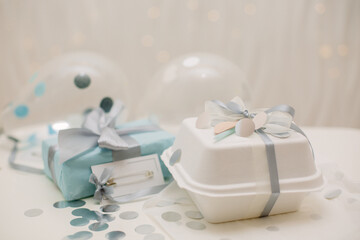 a gift in a blue and white box with a card for congratulations and balloons with confetti