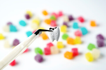 Close up Cavity and tooth decay pinching by clamp with colorful sweet sugar jelly candy on white background                          