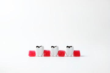 Decay and cavities teeth between sweet sugar red jelly instead of gum on white background, poor dental healthy affects to the mouth, gum and teeth