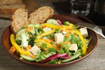 Delicious salad with lentils, vegetables and cheese on wooden table, closeup
