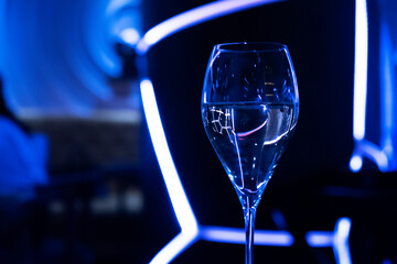 A glass of wine on the bar. Blue neon in the club restaurant close-up. Alcohol at the party