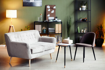 Empty chair and sofa iin front of small table in office of psychologist